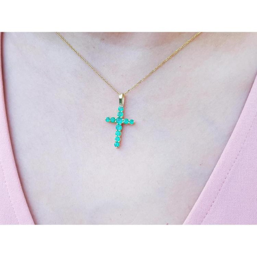 18K yellow gold cross pendant necklace with genuine emeralds on a woman's chest.