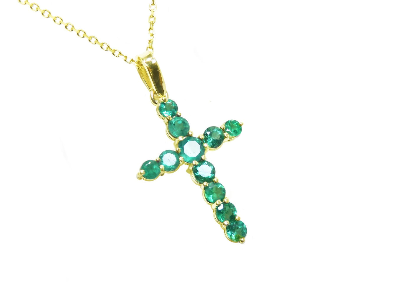 A 18k yellow gold emerald cross pendant necklace on topside position view.