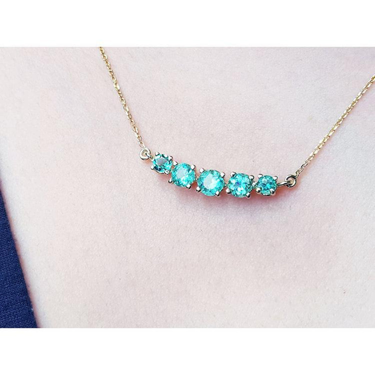14K gold necklace with five round, medium light green Colombian emeralds, graduated in size.