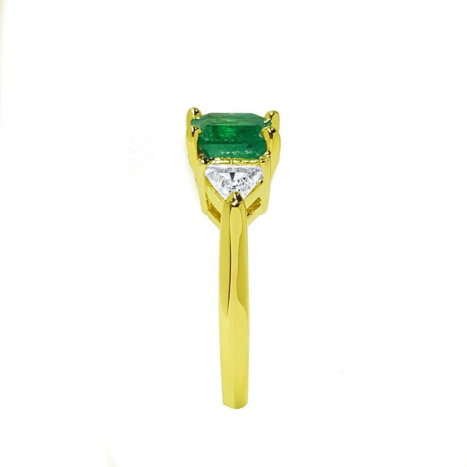 18K yellow gold three-stone ring with a vibrant emerald and two trillion-cut diamonds.