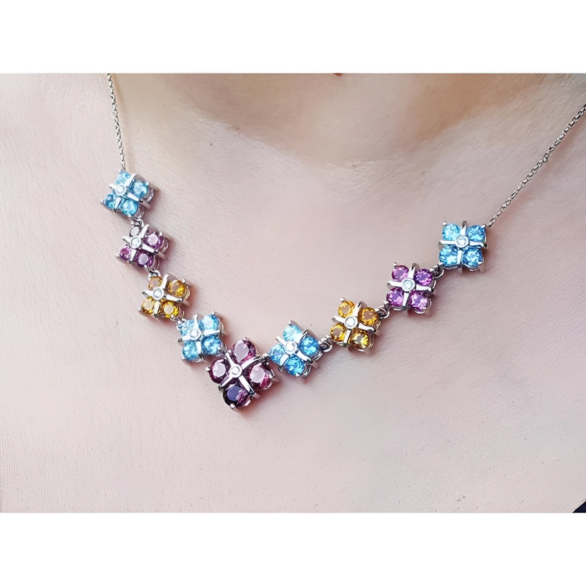 18K white gold necklace with tri-colored topaz X-cluster links on a model's neck.
