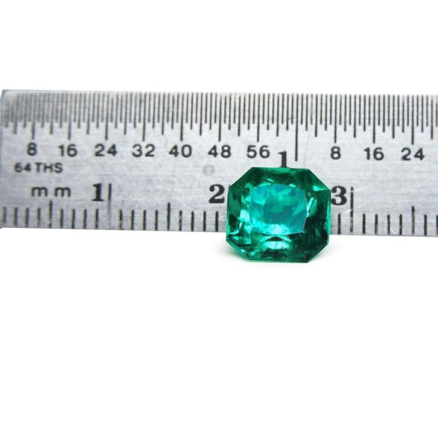 2.45 ct GIA certified Asscher cut emerald, vibrant bluish-green, next to a ruler for scale.