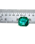 2.45 ct GIA certified Asscher cut emerald, vibrant bluish-green, next to a ruler for scale.