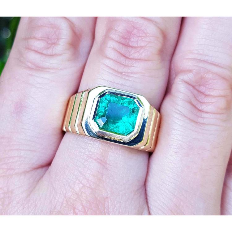 A GIA certified natural colombian emerald men's ring crafted in 18k yellow gold on a hand.