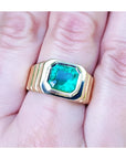 A GIA certified natural colombian emerald men's ring crafted in 18k yellow gold on a hand.
