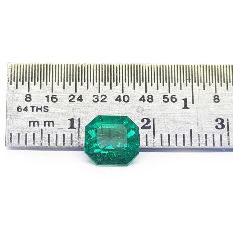 GIA certified 1.40 carat emerald-cut Colombian emerald with sparkling bluish-green color, next to a ruler.