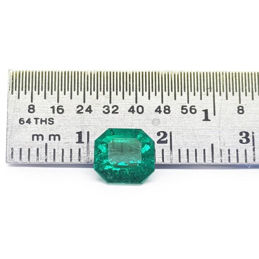 GIA certified 1.40 carat emerald-cut Colombian emerald with sparkling bluish-green color, next to a ruler.