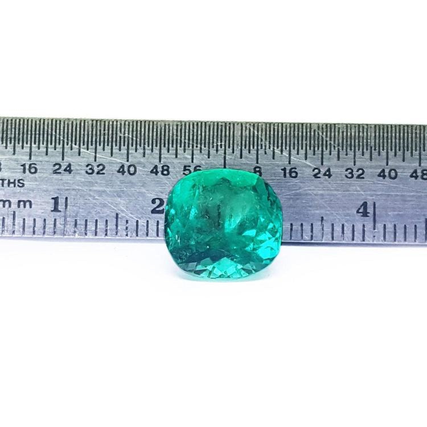 GIA certified 5.21 carat cushion-cut natural Colombian emerald with a bluish-green hue, shown against a ruler.