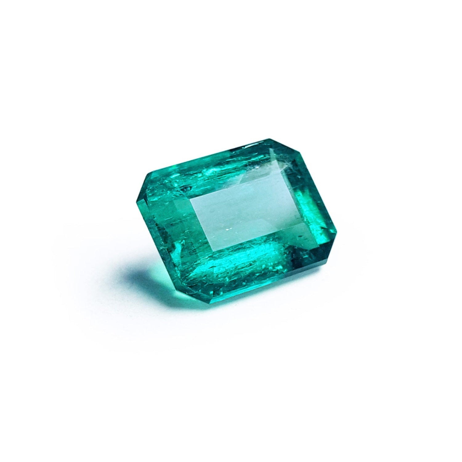 Vibrant bluish-green emerald-cut loose emerald from Muzo Colombia, 4.18 carats, on a white background.