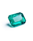 Vibrant bluish-green emerald-cut loose emerald from Muzo Colombia, 4.18 carats, on a white background.