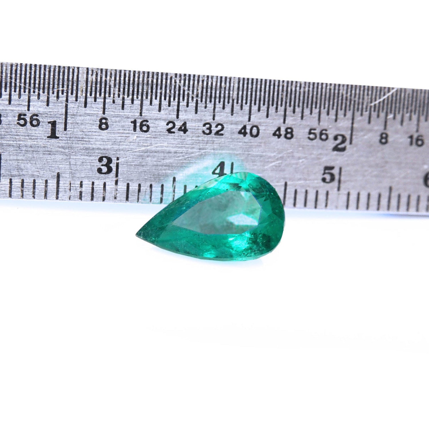 2.77 carat GIA certified pear cut Colombian emerald with vivid deep bluish-green hue, next to a ruler.