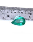 2.77 carat GIA certified pear cut Colombian emerald with vivid deep bluish-green hue, next to a ruler.