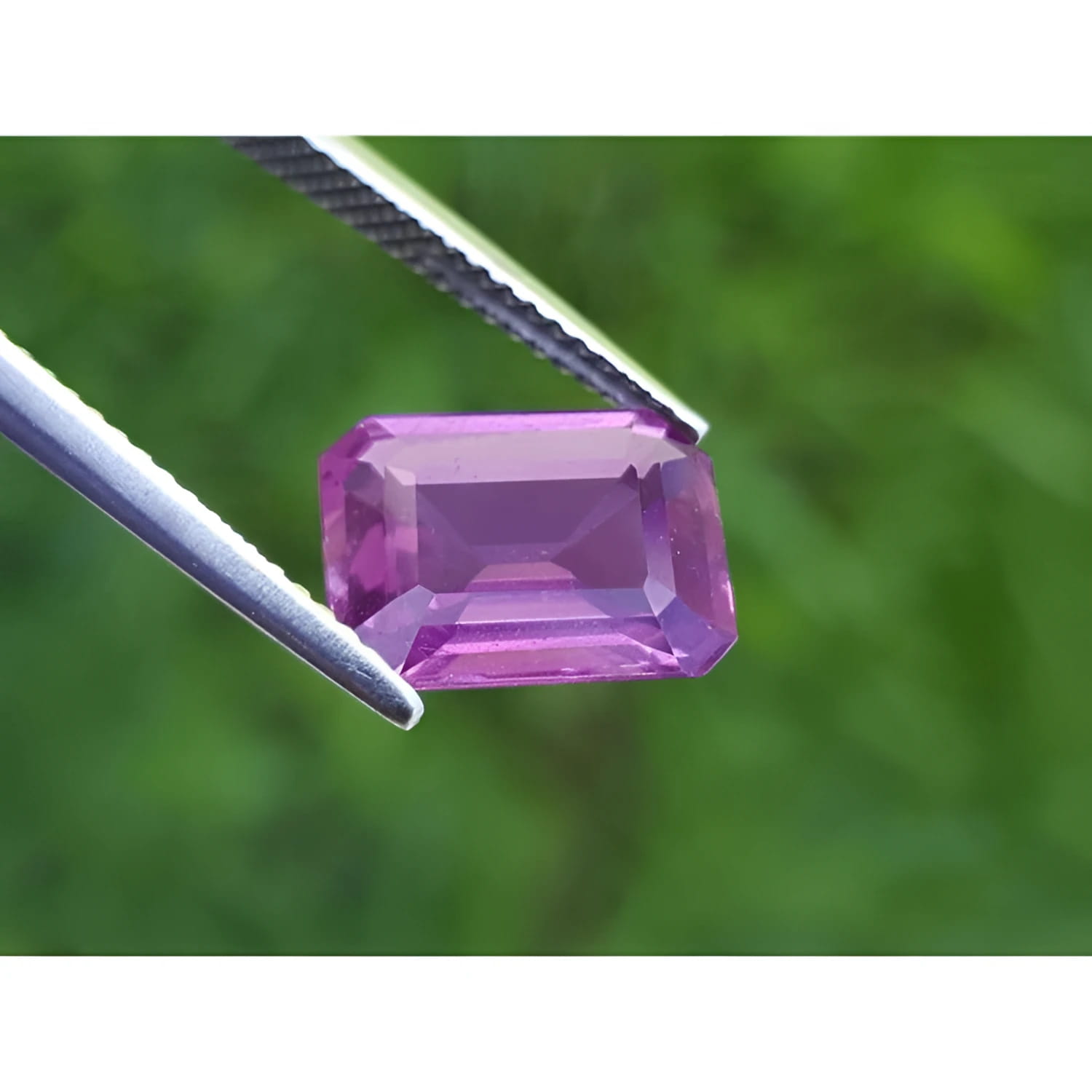 4.05 ct natural loose pink sapphire, emerald cut, held by tweezers.