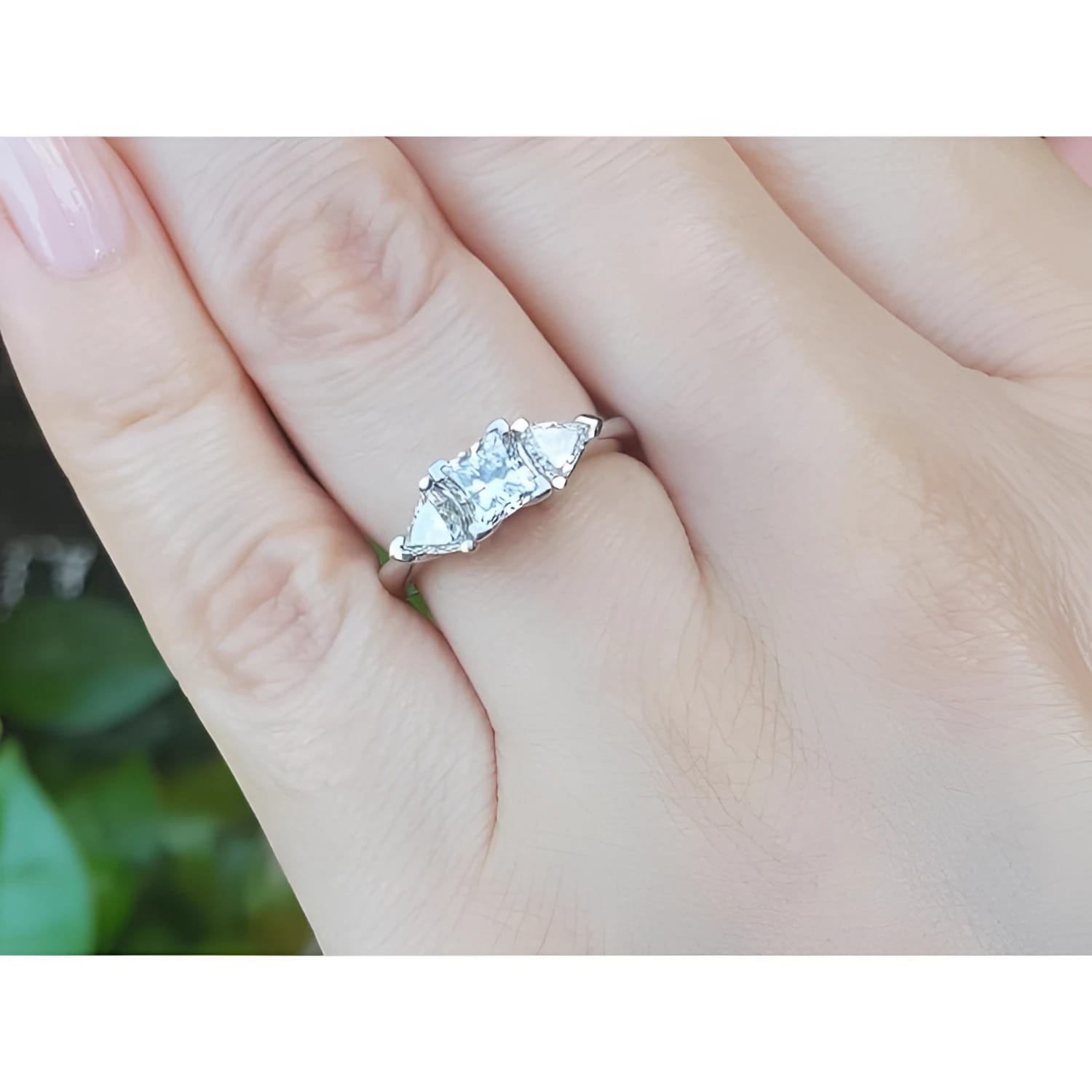 14K white gold ring with a princess cut center diamond and two trillion side diamonds on a hand.