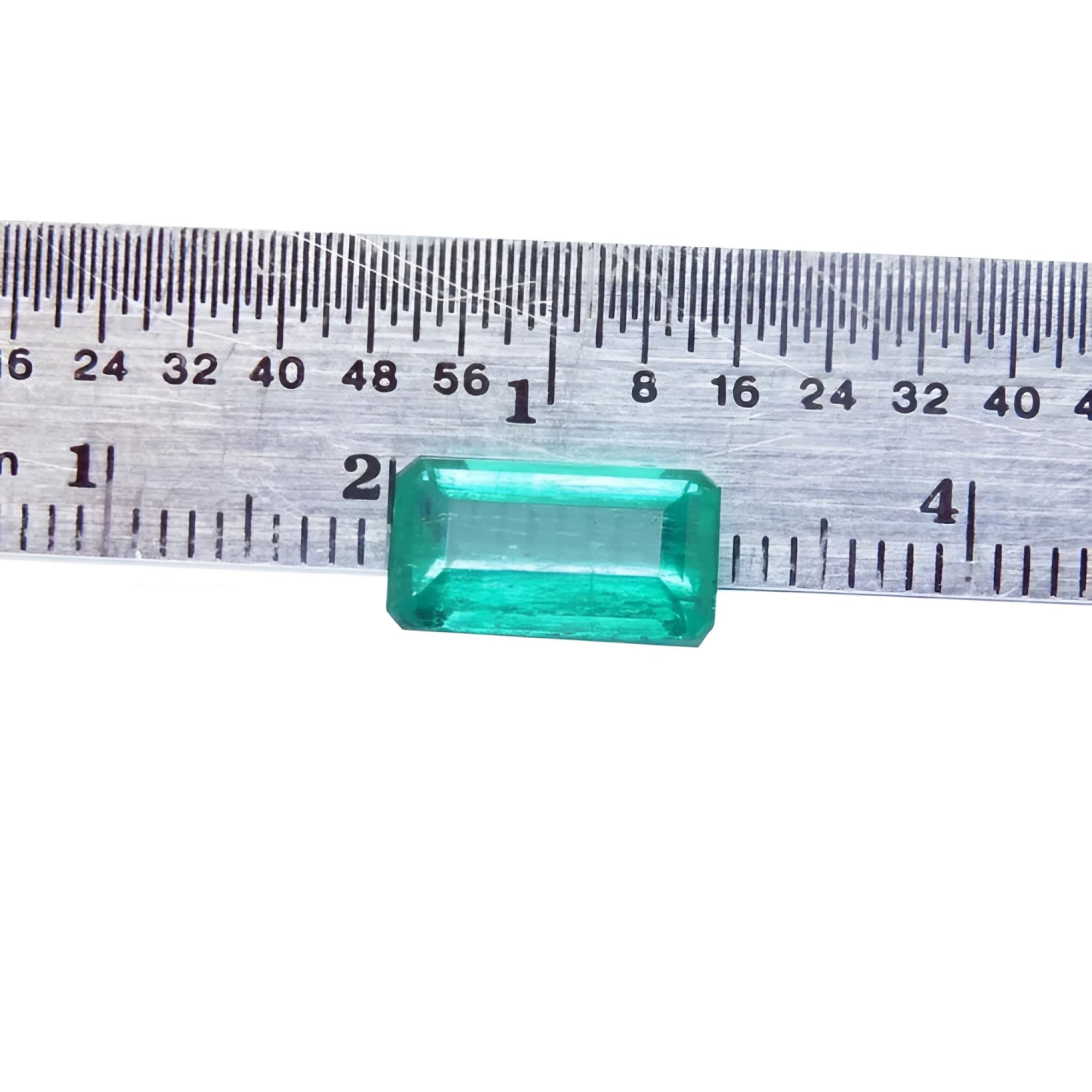 2.47 carat GIA certified loose Colombian emerald, sparkling bluish-green, rectangular cut, displayed against a ruler.