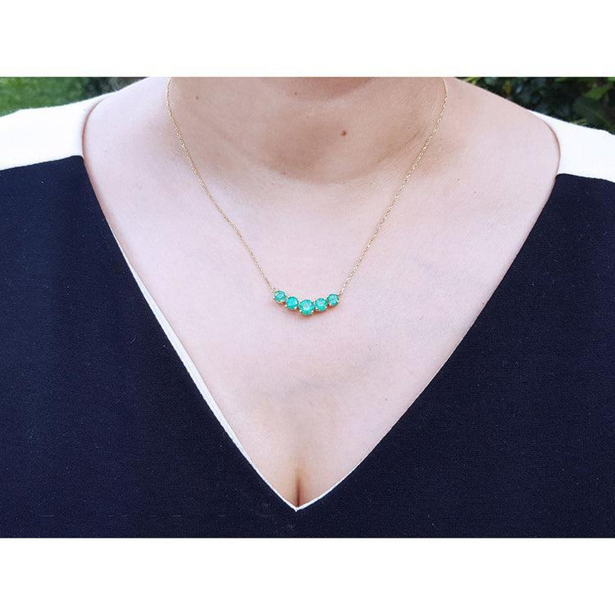 14K gold necklace with five round medium green Colombian emeralds in elegant basket settings.