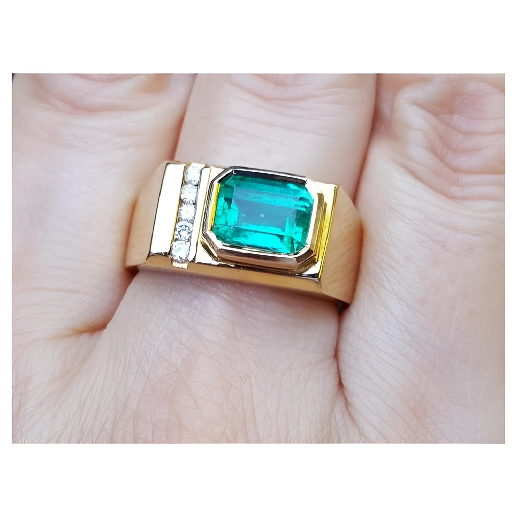 A 14k yellow gold ring for men with a bezel set natural emerald and accent diamonds.