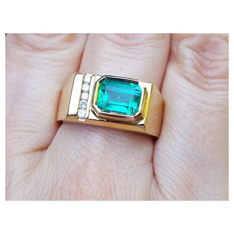 A 14k yellow gold ring for men with a bezel set natural emerald and accent diamonds.