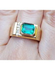 A 14k yellow gold ring for men with a bezel set natural emerald and accent diamonds.