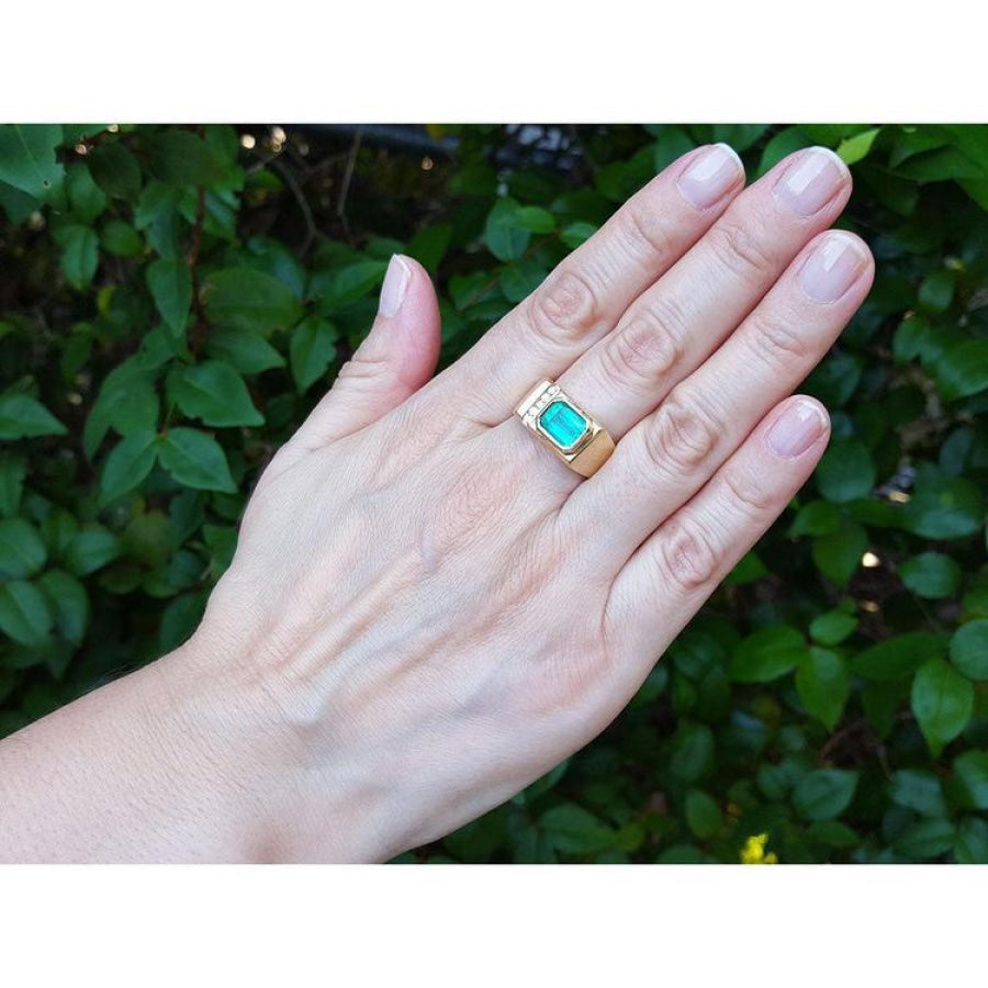 Men's 14K yellow gold ring with an east-west emerald-cut Colombian emerald and channel-set diamonds.