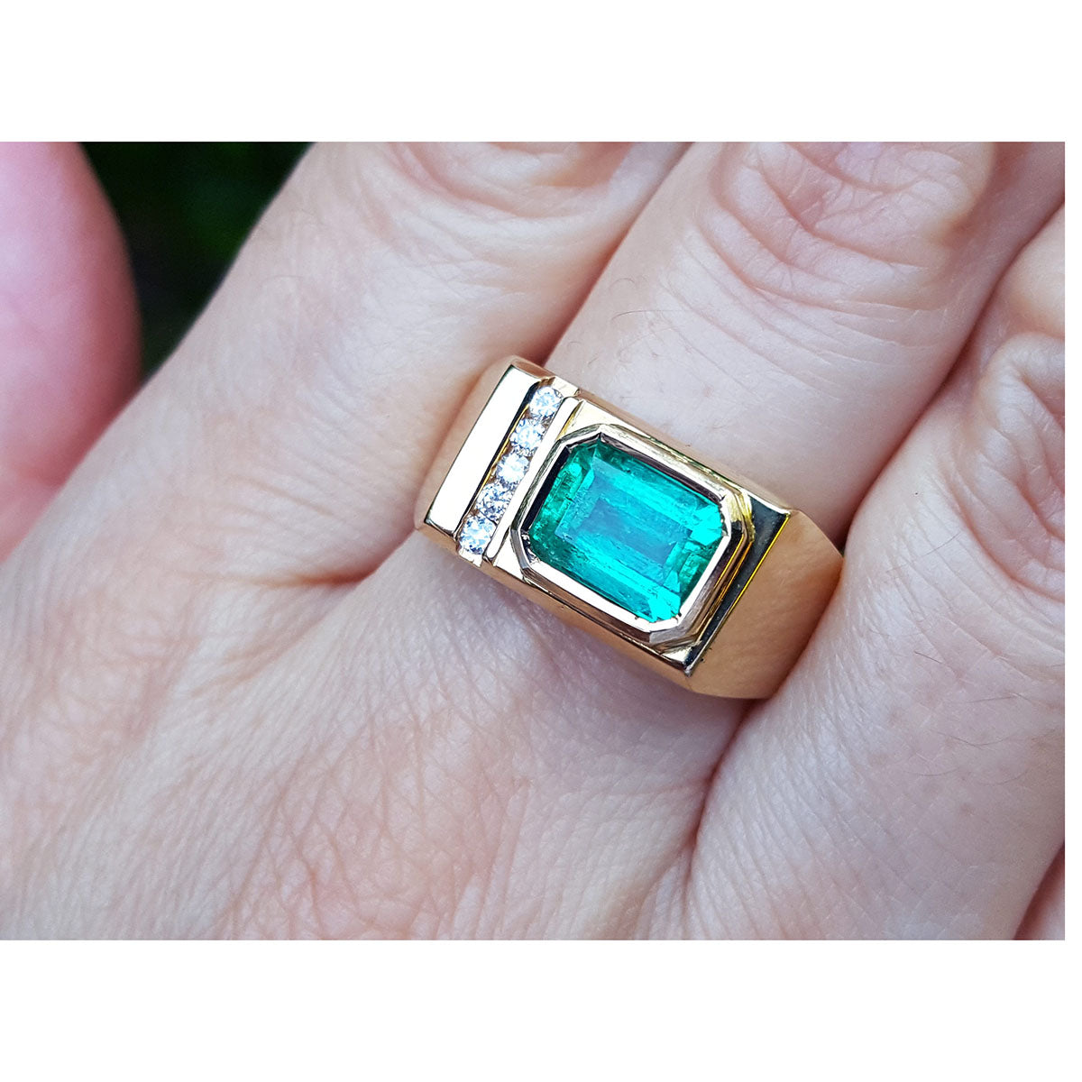 Men&#39;s yellow gold ring with a rectangular emerald bezel set on a hand