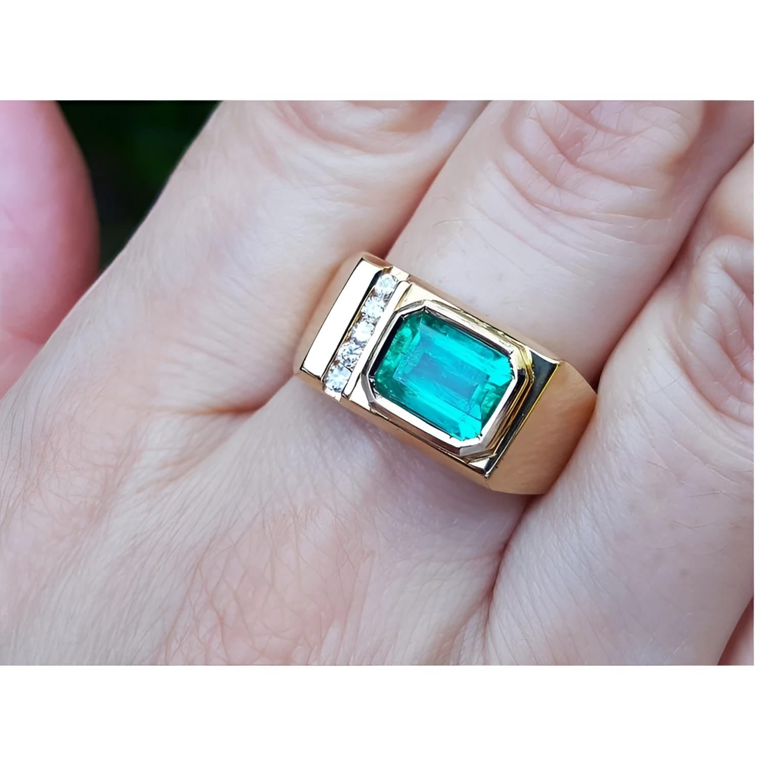 Men's 14K yellow gold ring with an east-west emerald-cut Colombian emerald and channel-set diamonds.