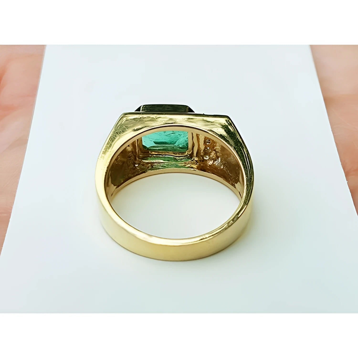 Men's 14K yellow gold ring with an east-west emerald-cut Colombian emerald and channel-set diamonds.