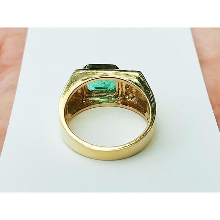 Men's 14K yellow gold ring with an east-west emerald-cut Colombian emerald and channel-set diamonds.