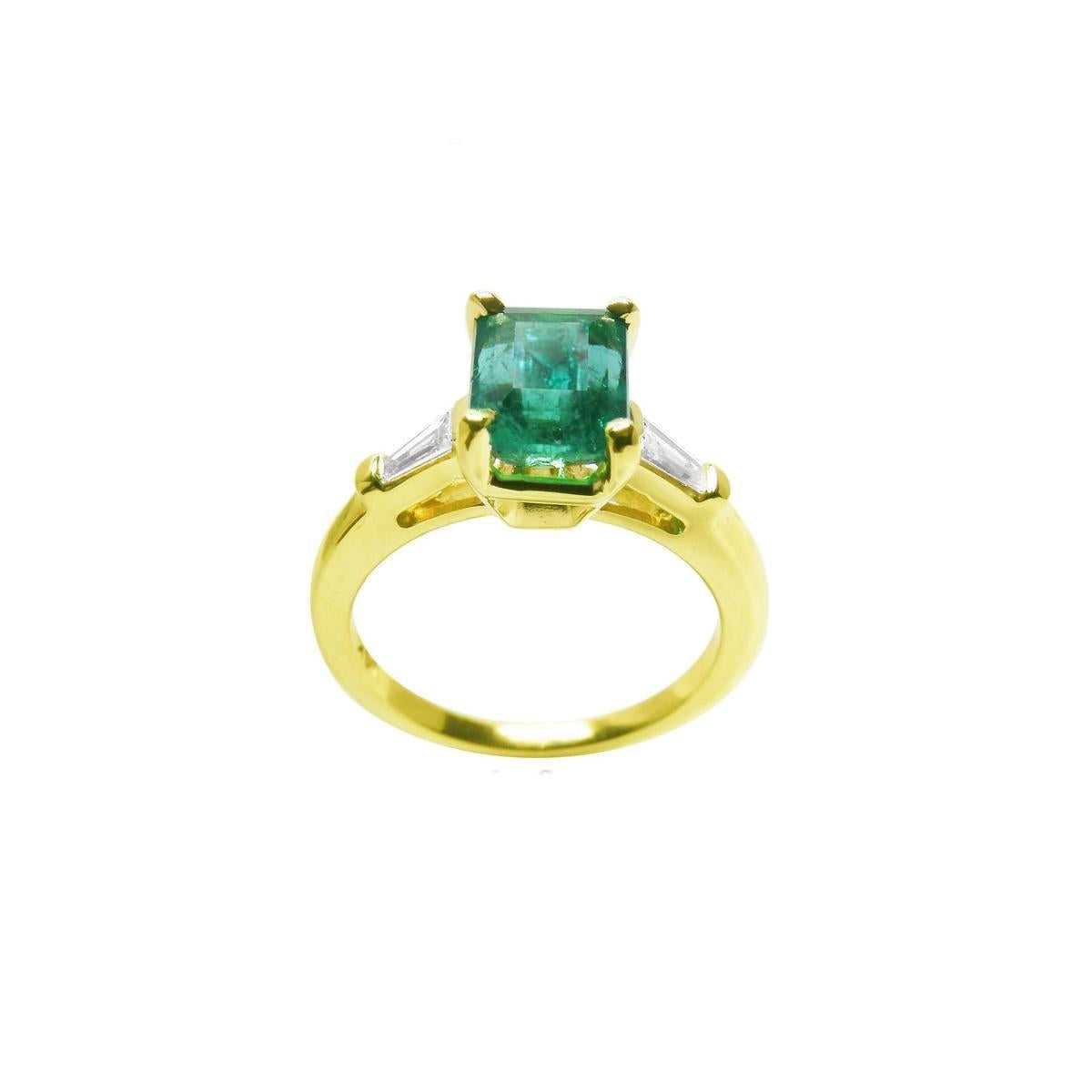 A 14k yellow gold ring with a natural colombian emerald on a white background.