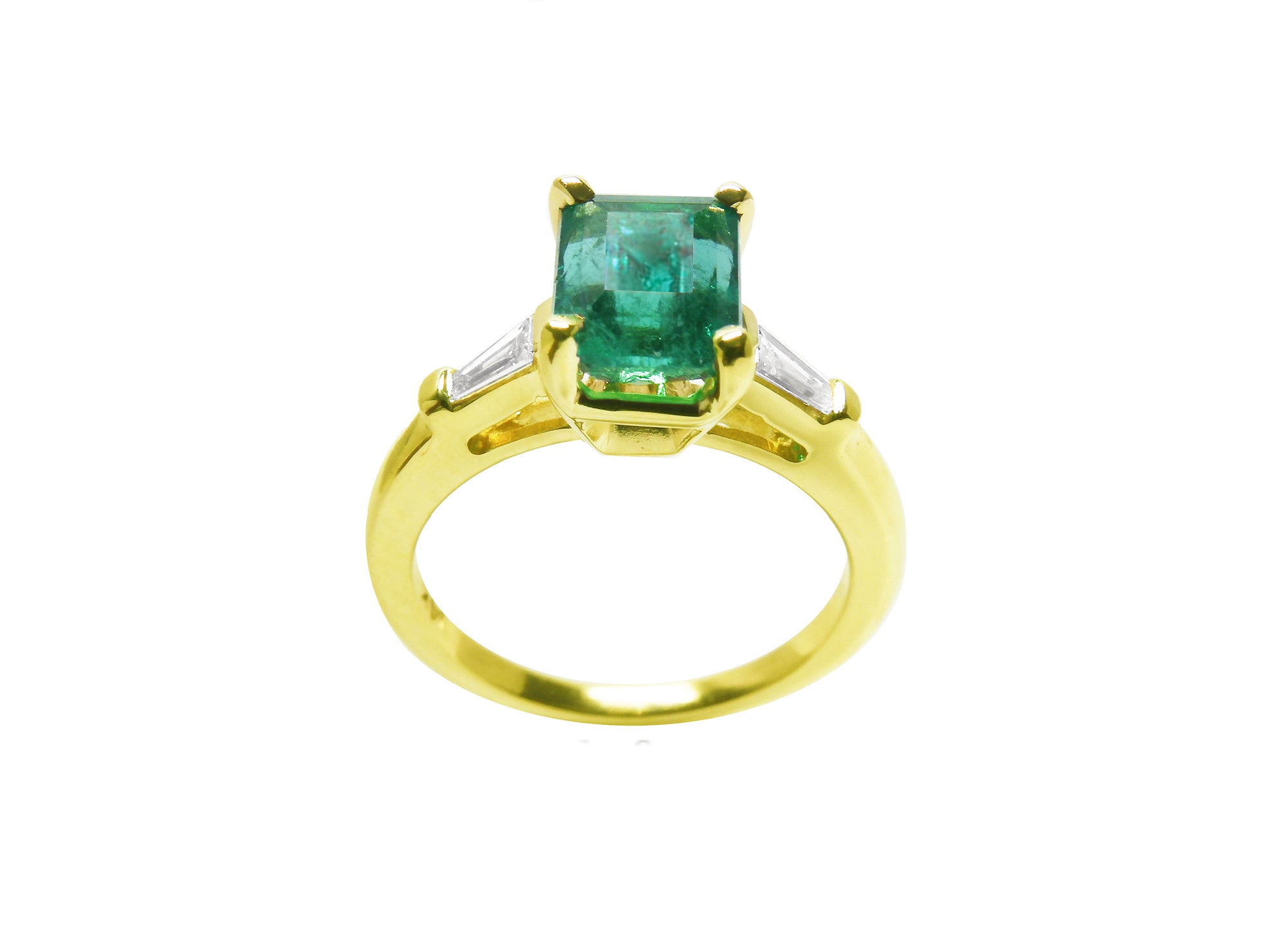 A 14k yellow gold ring with a natural colombian emerald on a white background.