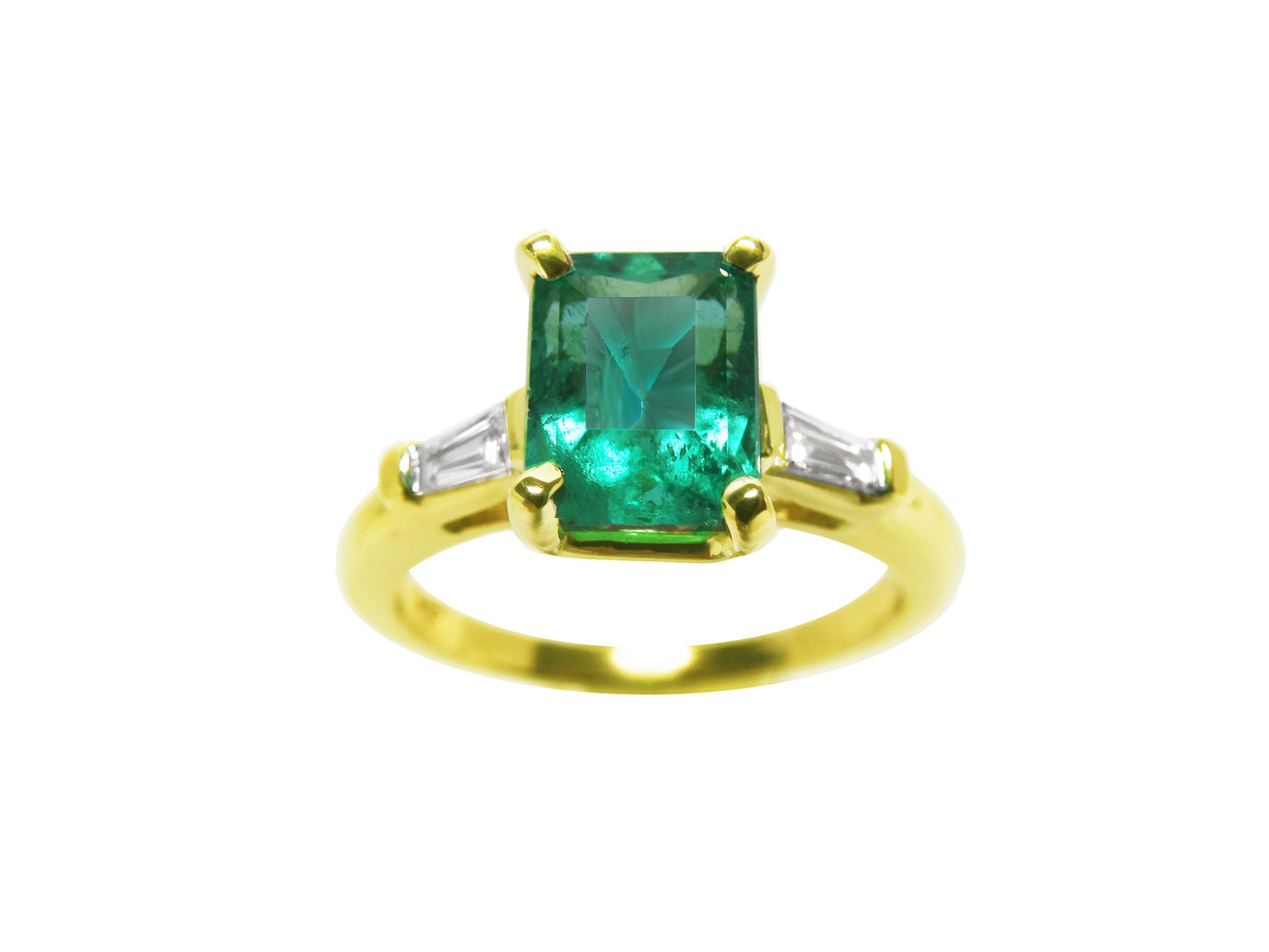A front top view of an emerald gold ring with tapered baguettes side diamonds on a white background.