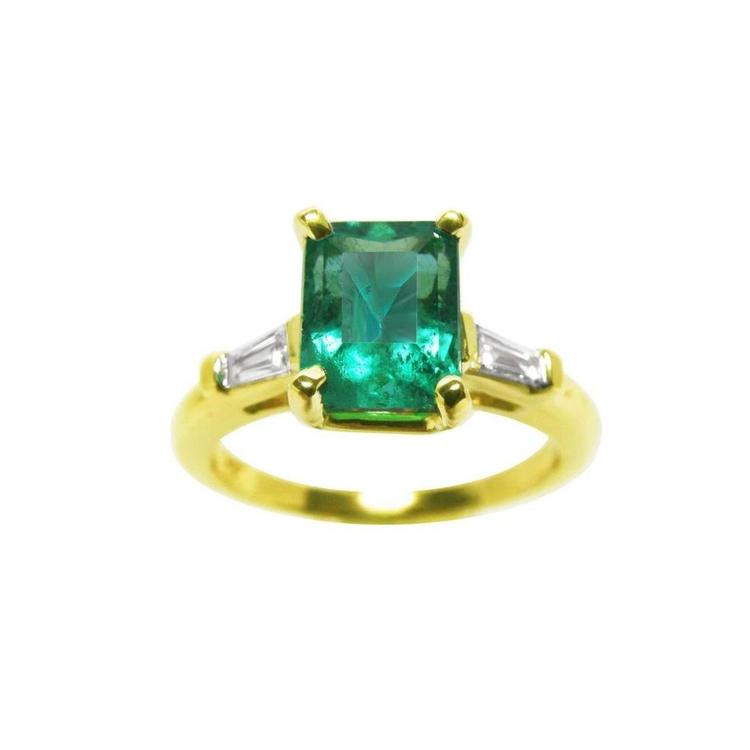 Natural emerald ring with tapered baguettes side diamonds crafted in 14k yellow gold.
