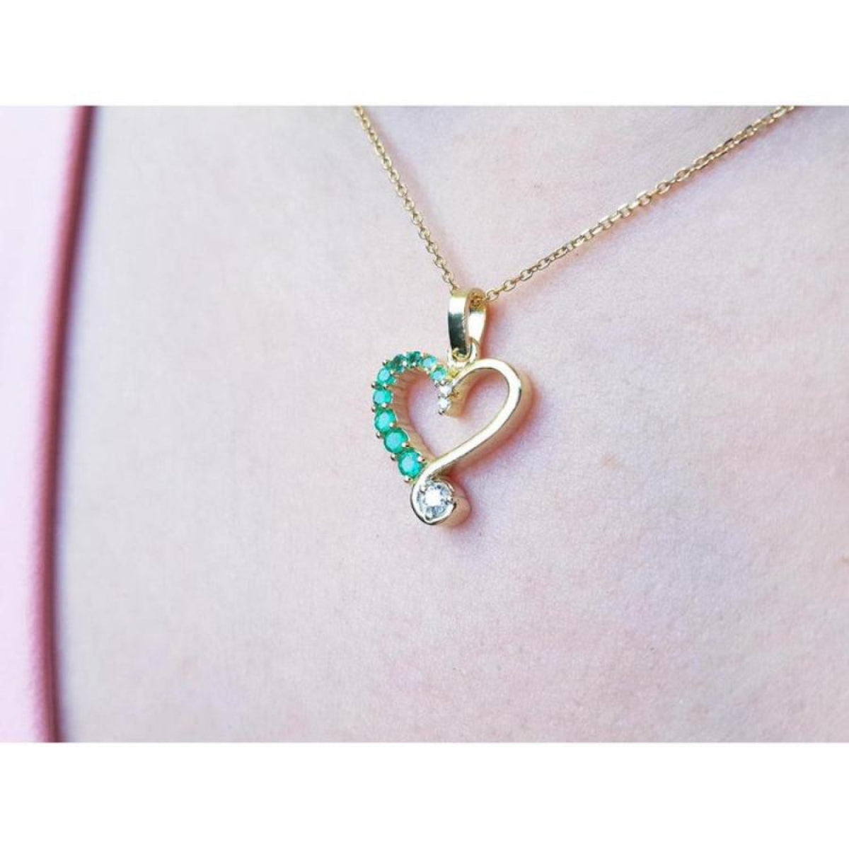 18K yellow gold heart pendant with natural emeralds and a brilliant-cut diamond, worn on a delicate chain.