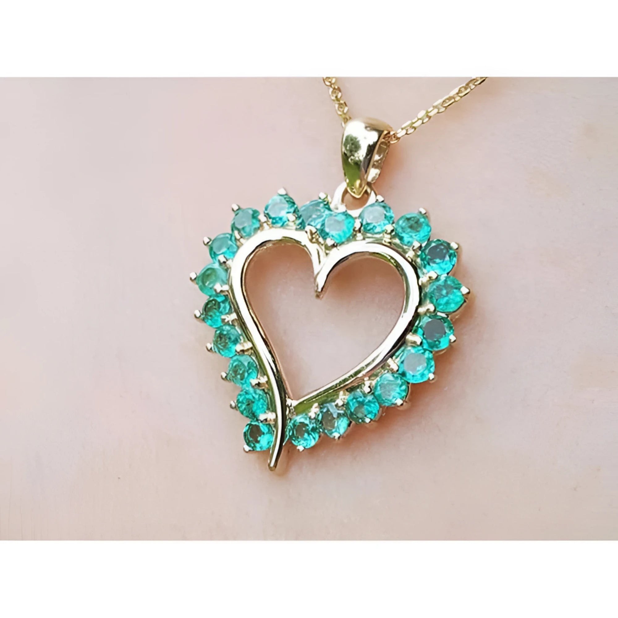 Heart-shaped pendant round colombian emerald stones on a light pink background