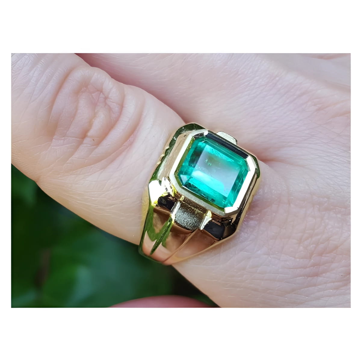 An 18k yellow gold men’s ring featuring a square natural Colombian emerald in a bezel setting, elegantly worn on the finger.