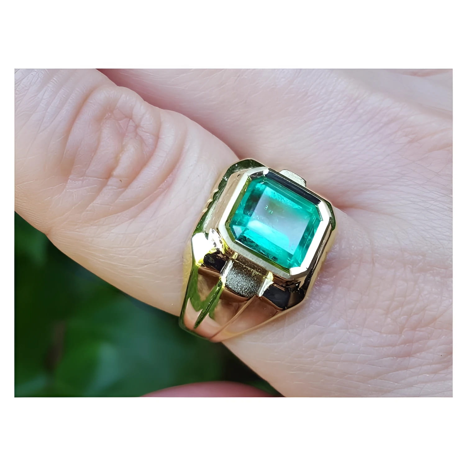 An 18k yellow gold men’s ring featuring a square natural Colombian emerald in a bezel setting, elegantly worn on the finger.