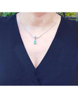Pear shaped emerald and diamond necklace in 14K white gold on a woman's neck.