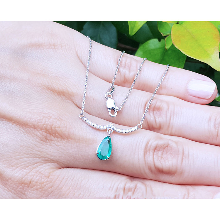 Pear cut necklace natural Colombian emerald dangling from a wavy central bar with diamonds pave set in 14k white gold