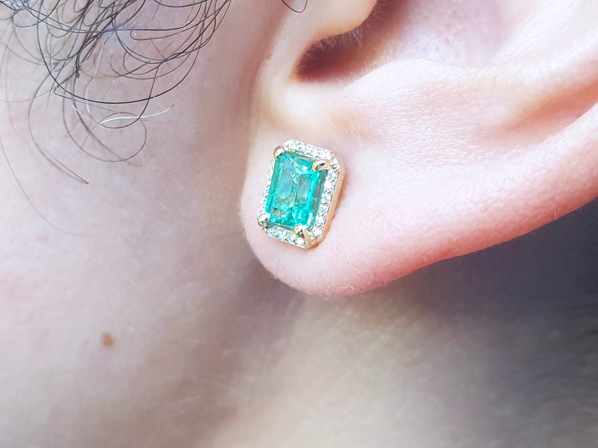 Close-up of an ear wearing a Colombian emerald stud earring.