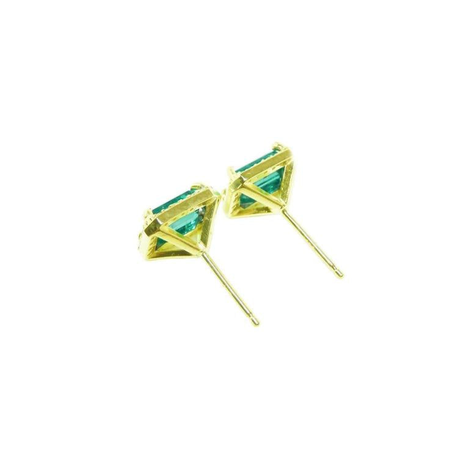 Emerald stud earrings with diamond halo in 14k yellow gold.