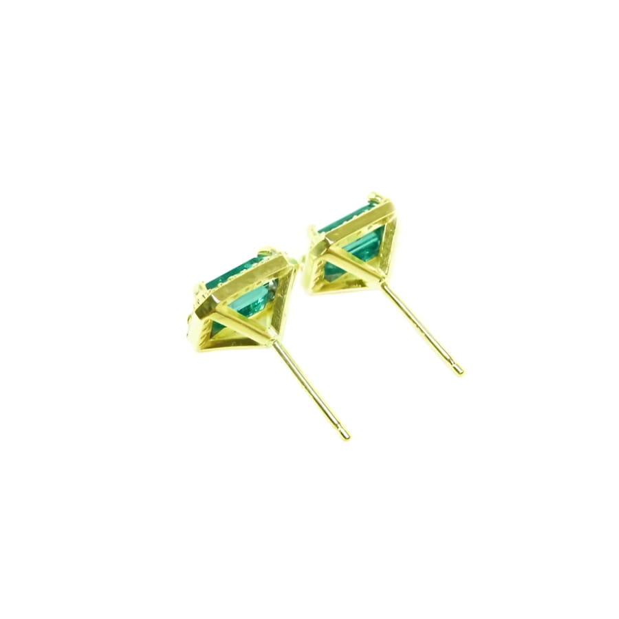 Emerald stud earrings with diamond halo in 14k yellow gold.