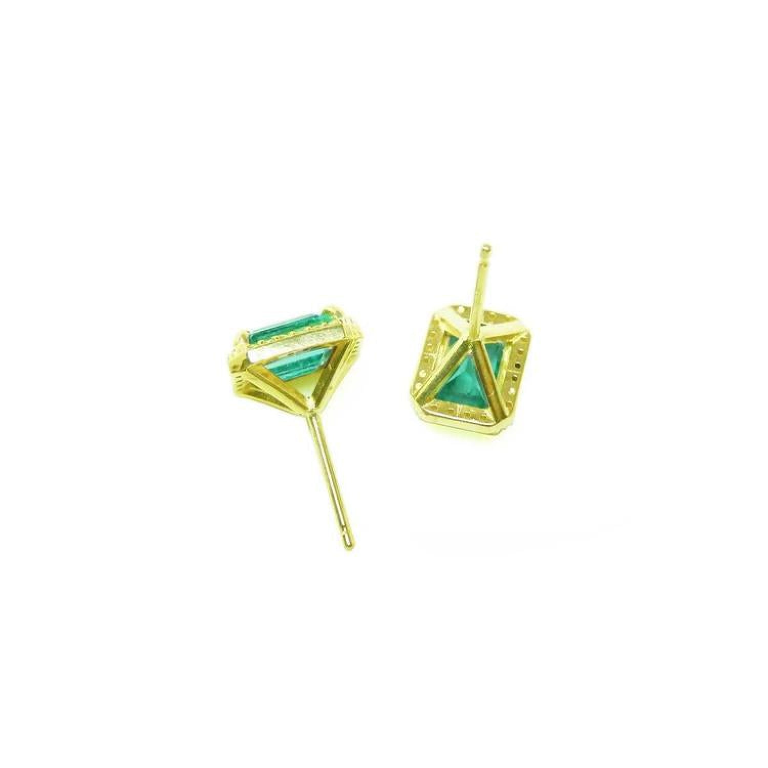 Emerald stud earrings with diamond halo in 14k yellow gold, featuring baguette-cut emeralds.