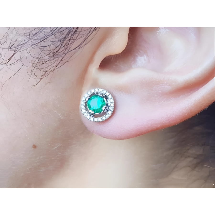 1.06 ct deep bluish-green Colombian emerald stud earring with diamond halo and secure screw back on an ear.