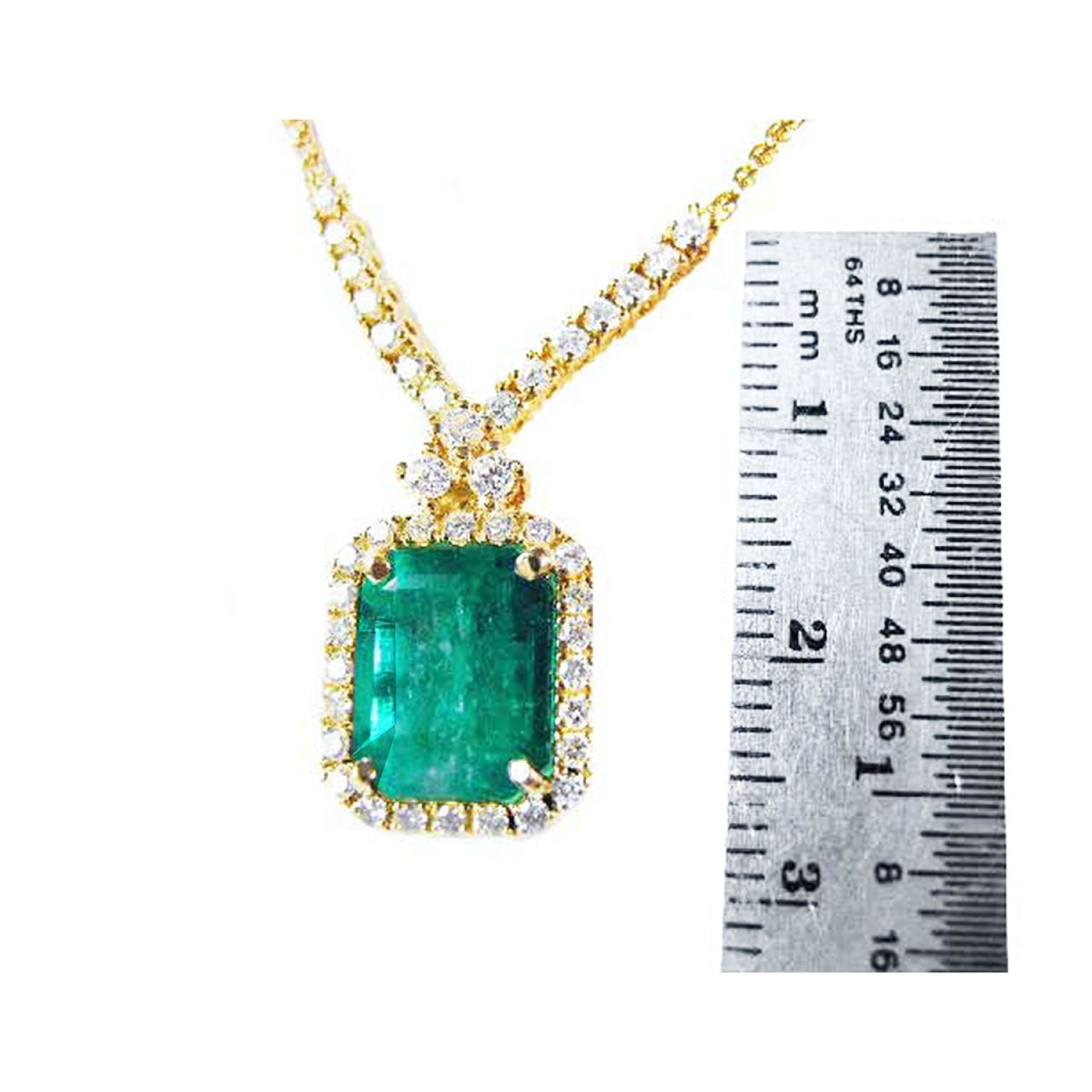 3.43 ct emerald halo necklace with natural diamonds on a 14K yellow gold chain, shown next to a ruler.
