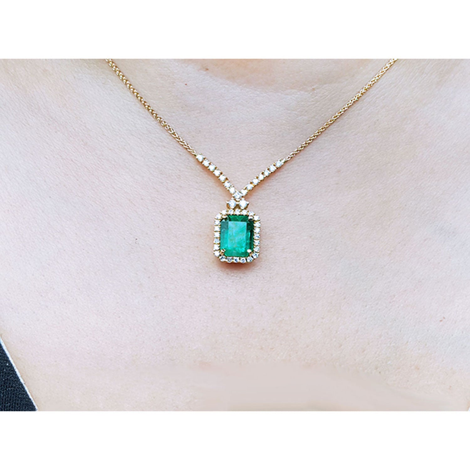 3.43 ct emerald halo necklace with natural diamonds on a 14K yellow gold chain.