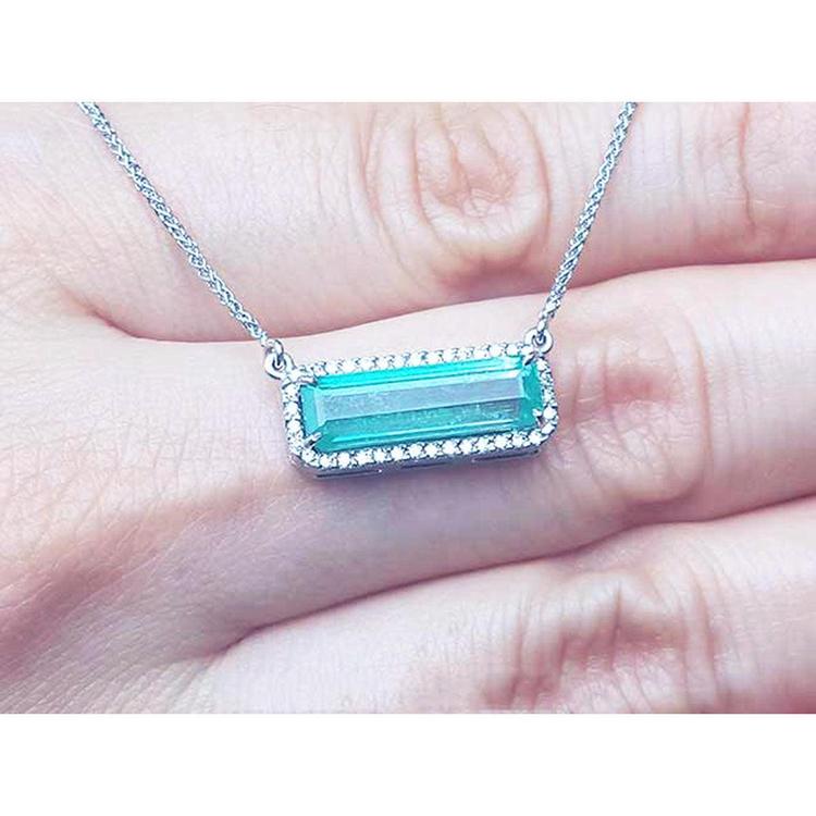 18K white gold necklace with a rectangular Colombian emerald and diamond halo, East-West design.