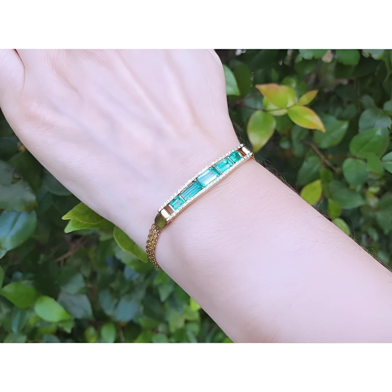 14K gold bracelet with five vibrant bluish-green emeralds and sparkling diamonds on a woman's wrist.