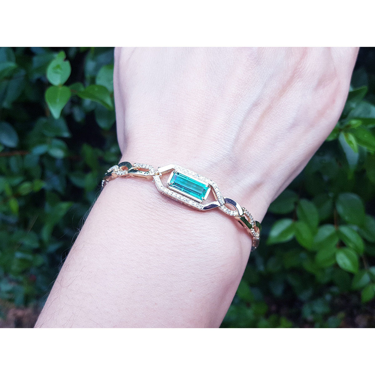 Bracelet with a genuine emerald on a wrist against a blurred green background