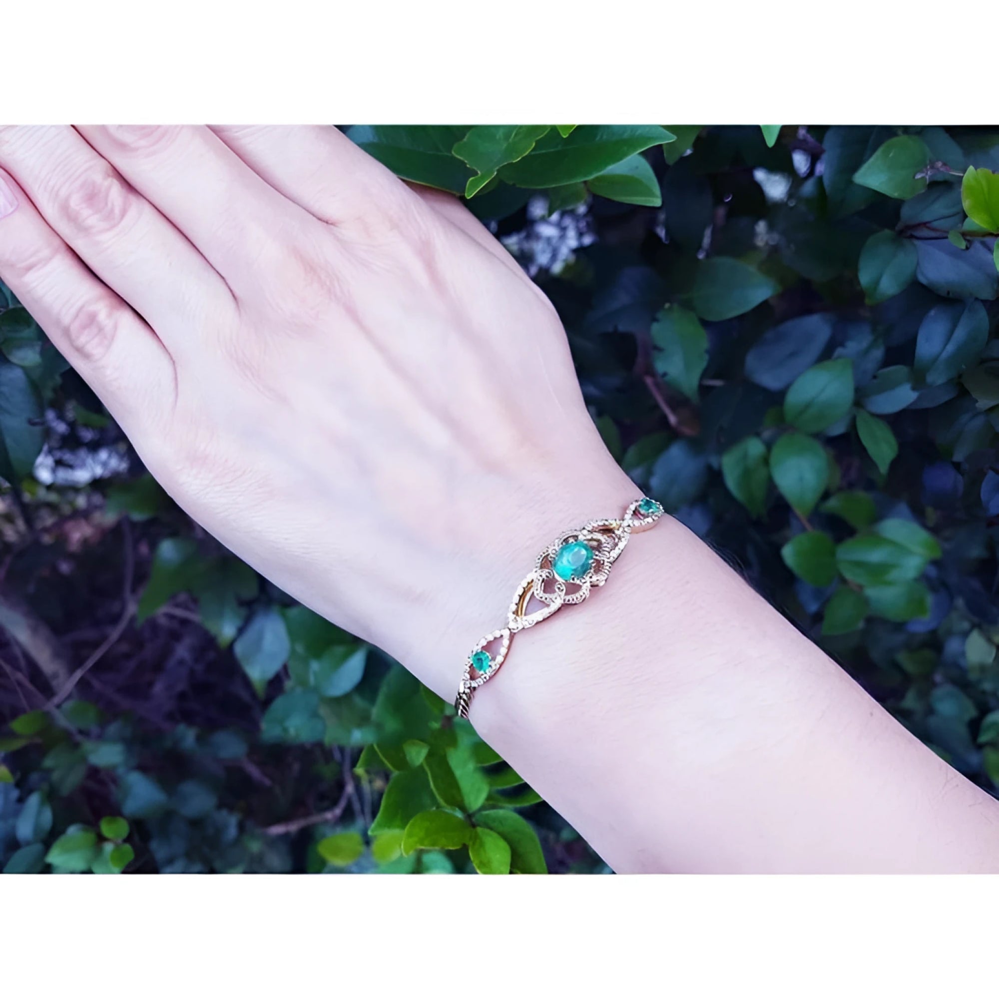 Vintage 14K yellow gold bracelet with oval emeralds and diamonds on a wrist.