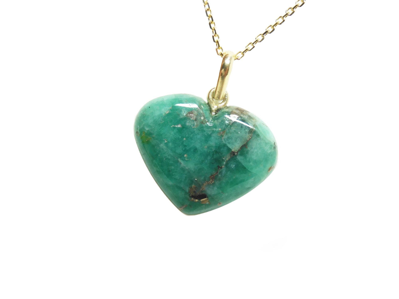 Heart-shaped cabochon emerald stone pendant on a gold chain on its left side view.